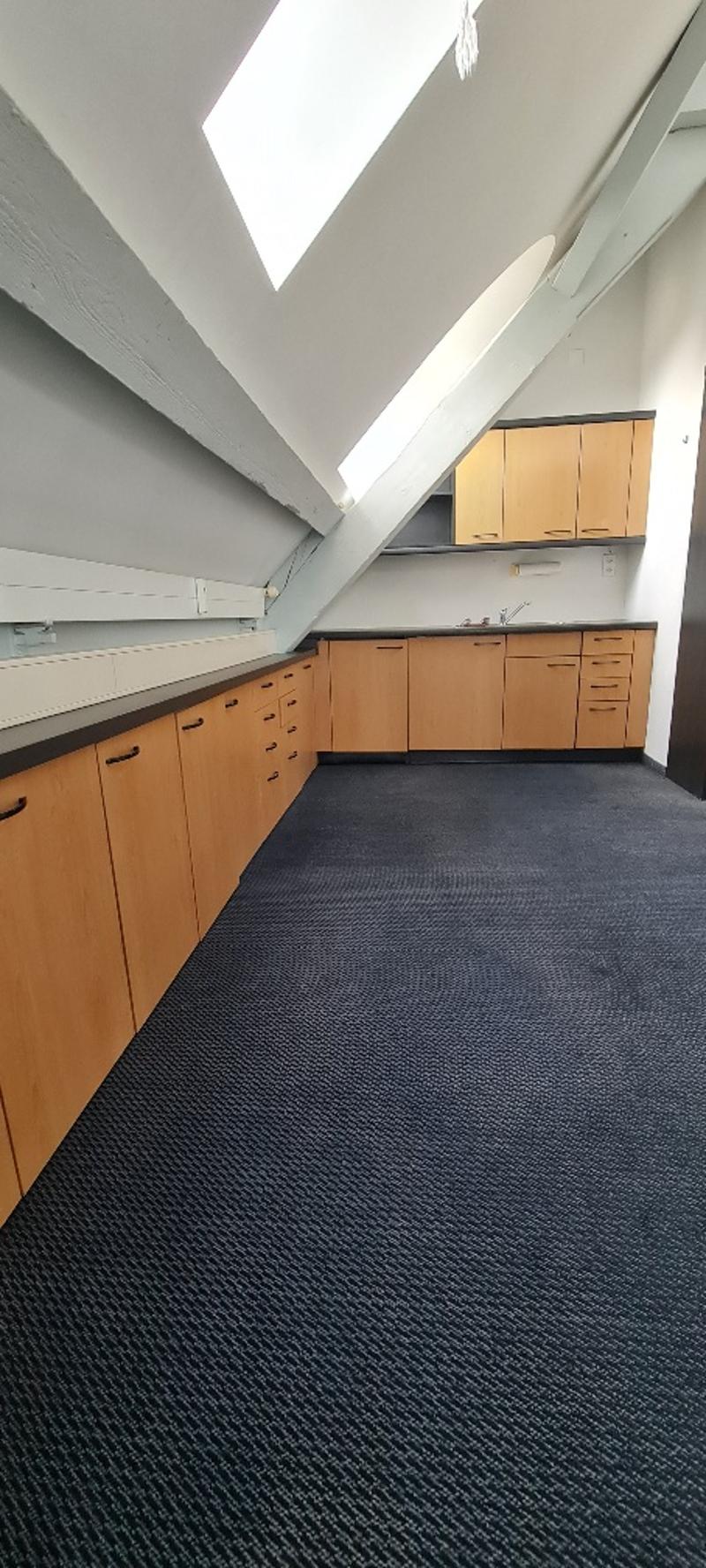 Empty room with wooden cabinets, dark blue carpeted floor, white ceiling, windows