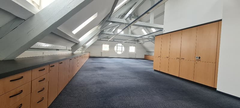 empty room with wooden cabinets, gray carpet, attic ceiling, beams, round windows