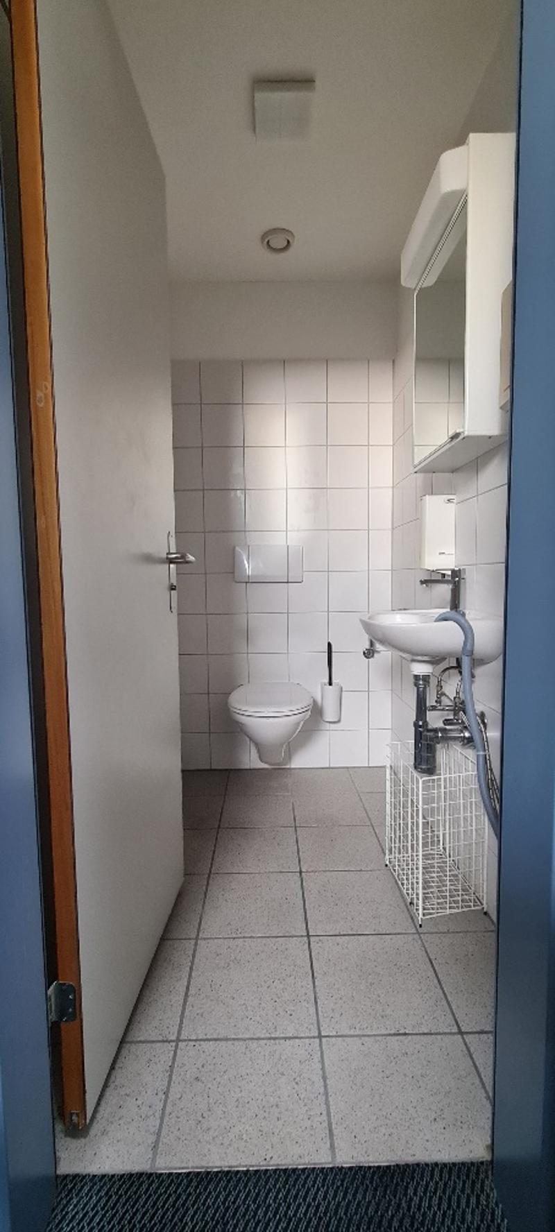 white tiled walls, white tiled floor, toilet, sink, open door