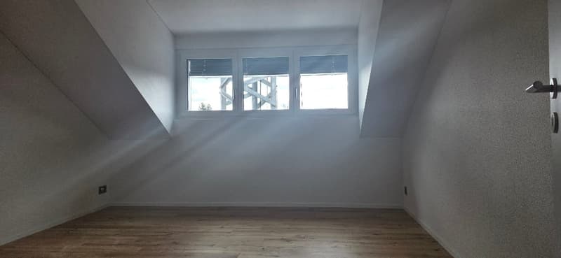 empty room, wooden floor, slanted ceiling, white walls, 2 windows, power outlet