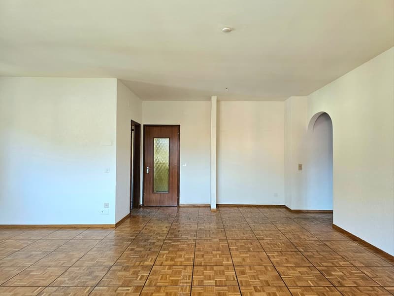 large open room, tiled floor, doorway, wall-mounted power outlets, white walls