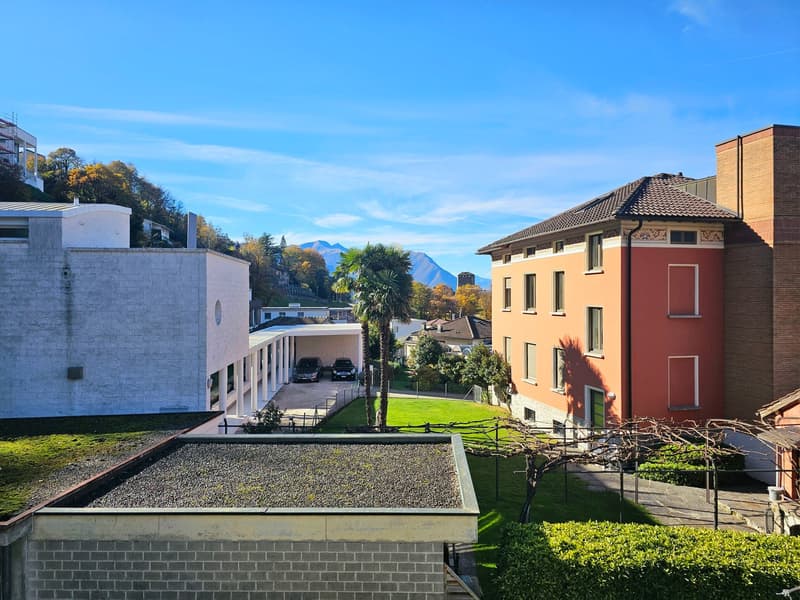 large building with garage, green roof, large windows, nearby grass lawn and plants