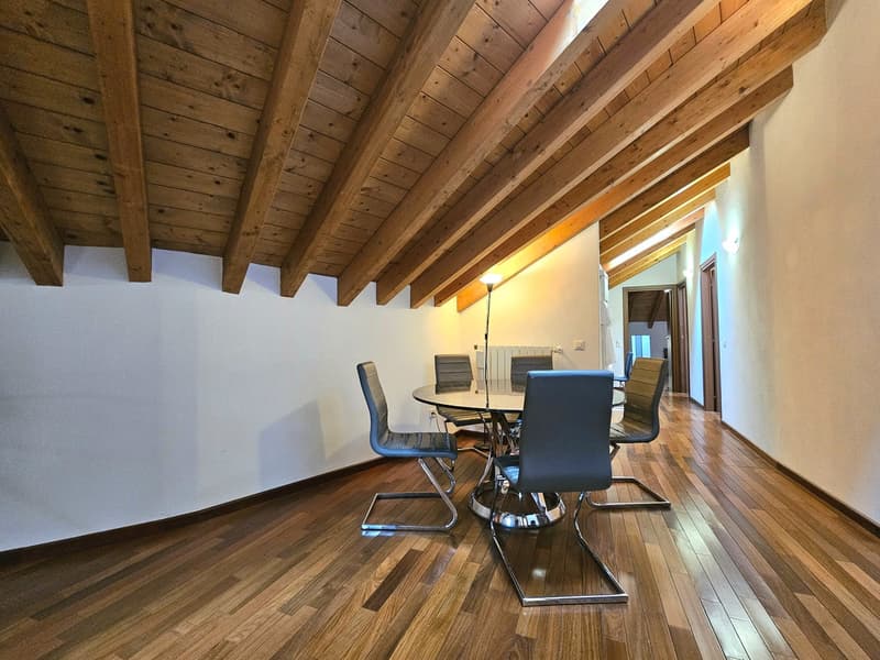 room with wooden floor, wooden beams on ceiling, round table and 6 chairs, lamp on the wall