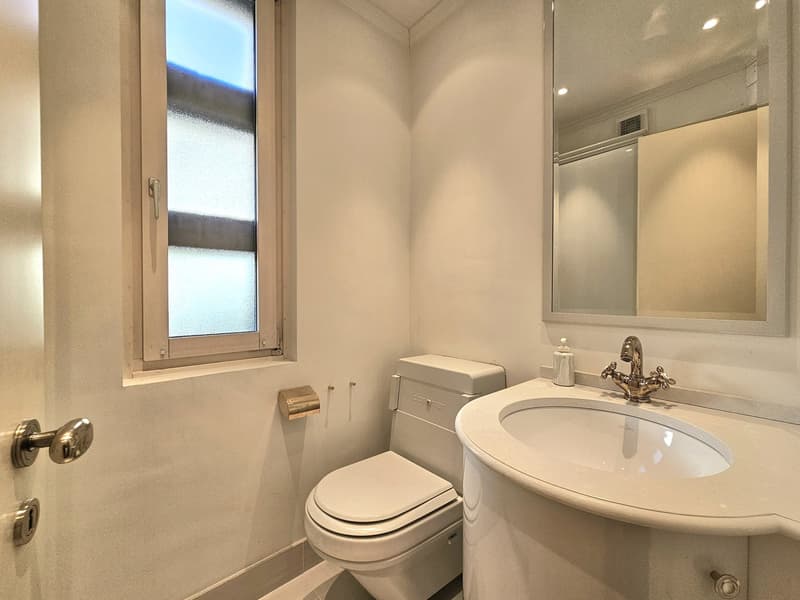 compact bathroom with toilet, sink, and mirror