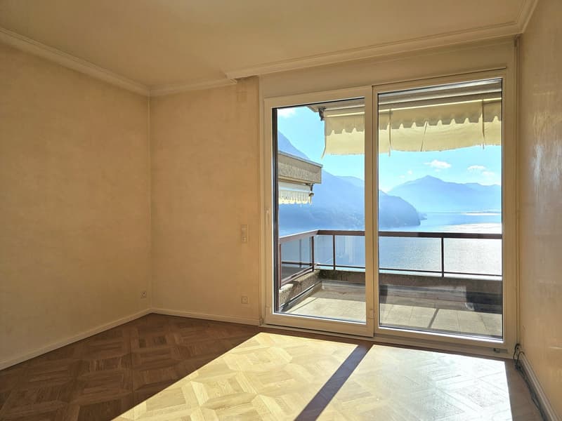 Large glass sliding doors leading to balcony, parquet floors, beige walls, balcony with metal railing