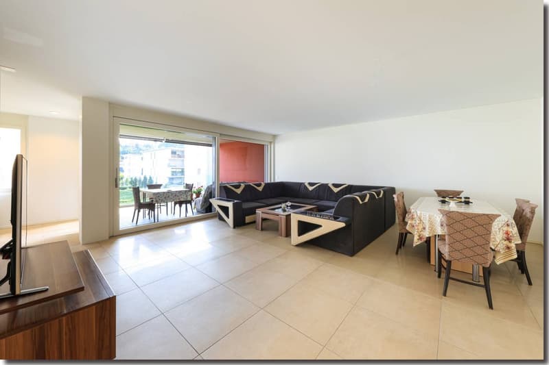 Living room with glass sliding door opening to balcony, a sofa, TV stand, coffee table, dining set