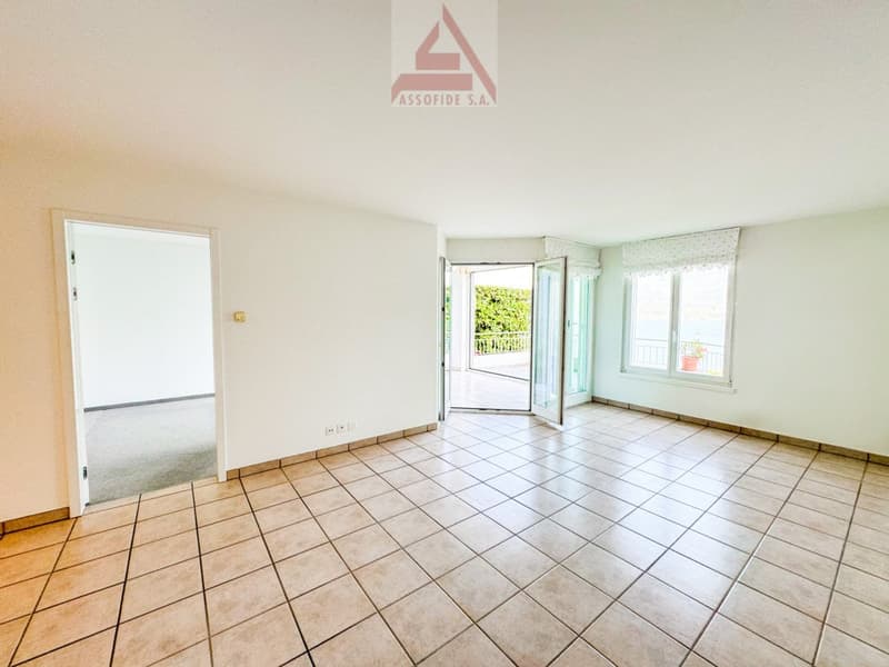 Spacious room with tile flooring, white walls, and large windows providing natural light. The room appears to be an open living or dining area.