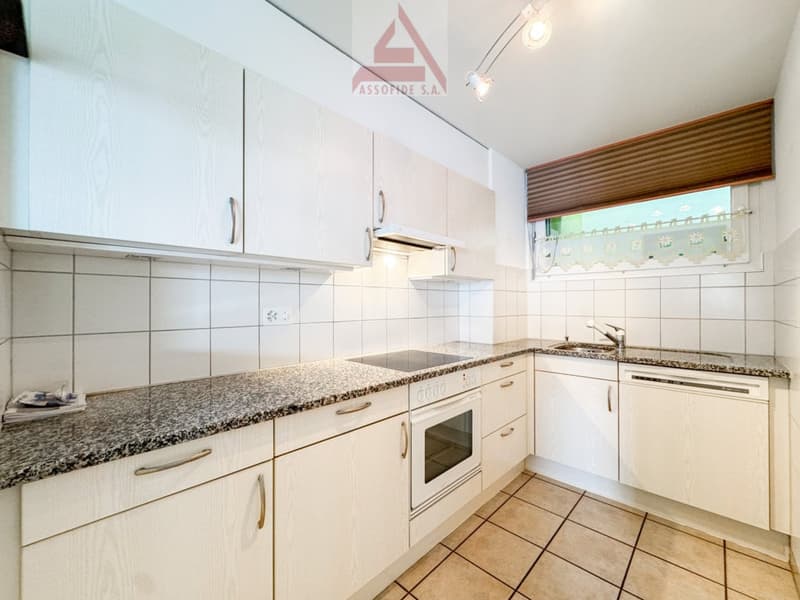 Spacious kitchen with white cabinets, granite countertops, built-in oven, and dishwasher
