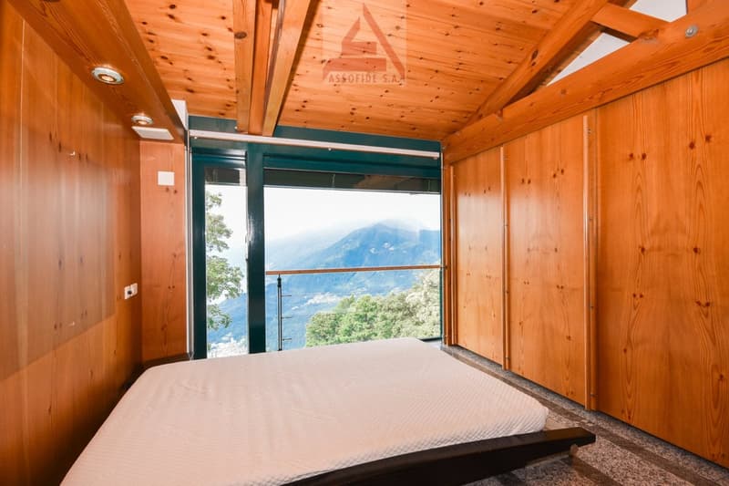 Spacious bedroom with wooden walls and ceiling, large windows offering a scenic mountain view
