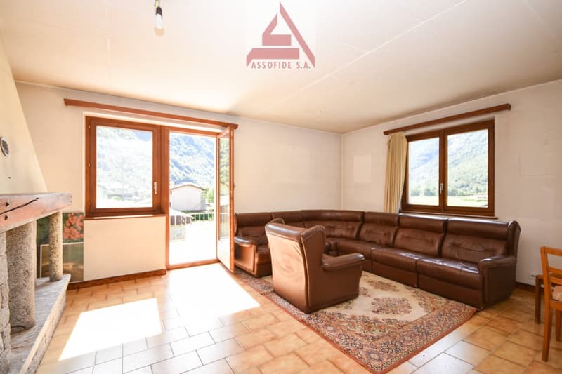 open space, large fireplace, windows to balcony, brown leather sofa, wooden chair