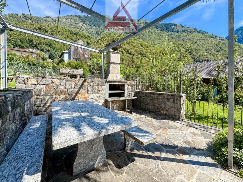 Stone seating area, outdoor table, stone bench, stone wall, fireplace, metal roofing, open area, mountains