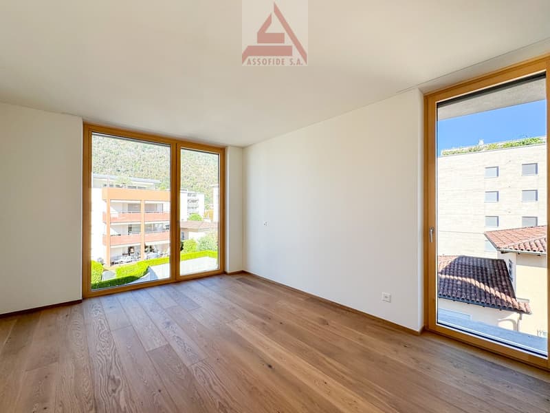 empty room, large windows, hardwood floors, views of nearby buildings