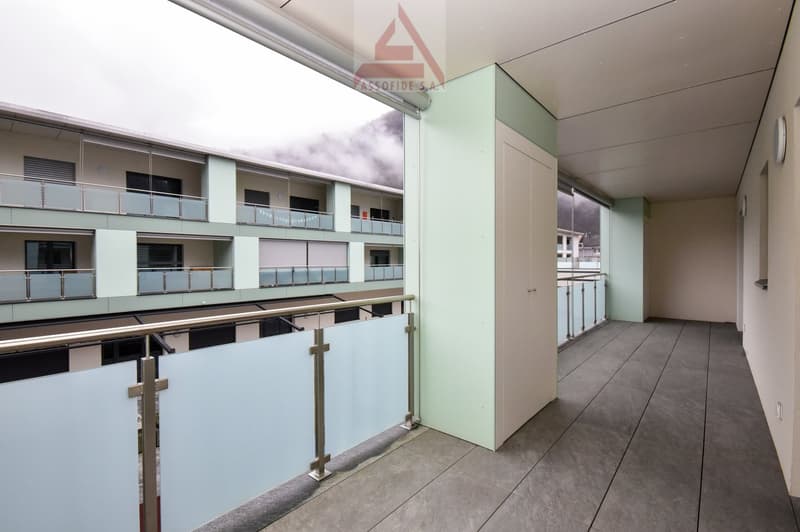 modern building with balcony, metal railings, tiled floor, green wall