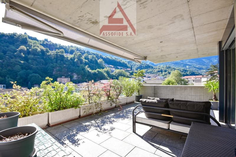 terrace with outdoor seating and table, concrete floor, greenery in white planters, shade, mountain view