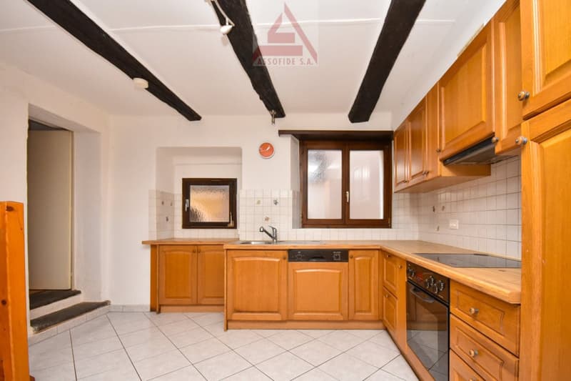 The kitchen has tiled floor and wall, wooden cabinets, sink with faucet, a dishwasher, and an oven.