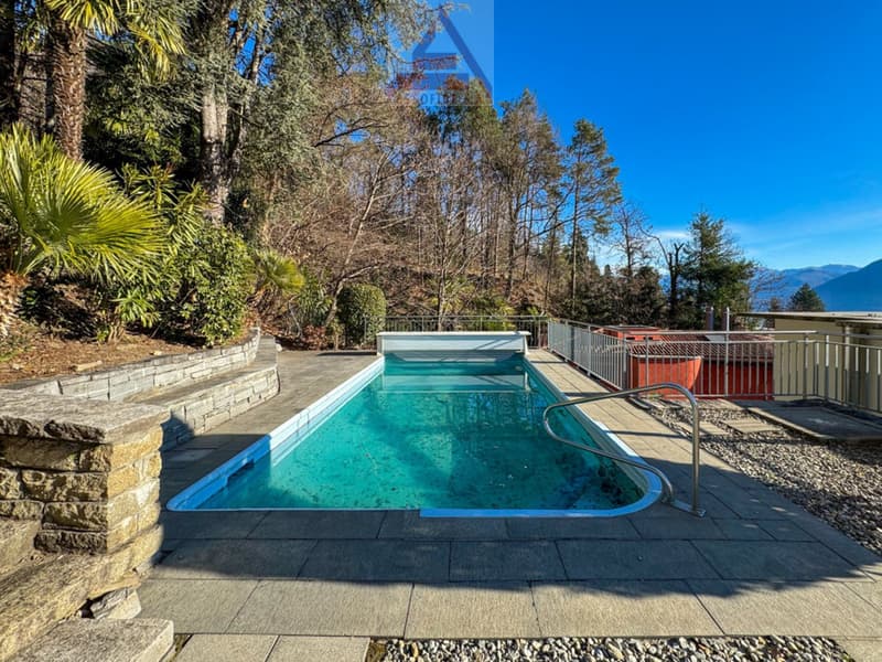 Outdoor swimming pool, metal fence, gravel path, stone bench, trees, plants, view of mountains