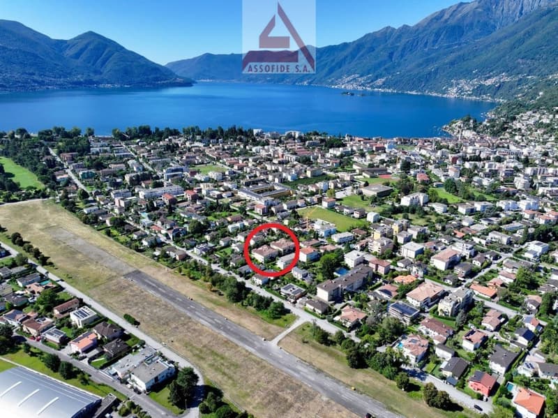 Aerial view of the city with many buildings, mountains in the distance, and a body of water.