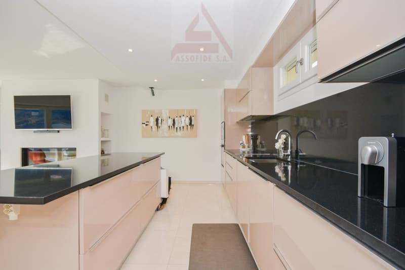 modern kitchen, black countertops, stainless steel appliances, fireplace, tiled floor, wall mounted TV