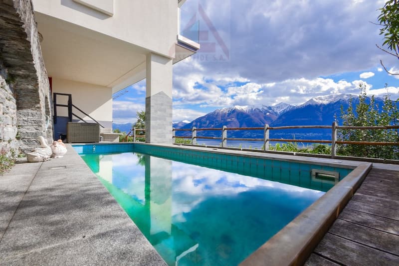 Swimming pool surrounded by wooden deck, mountains in background, clear sky