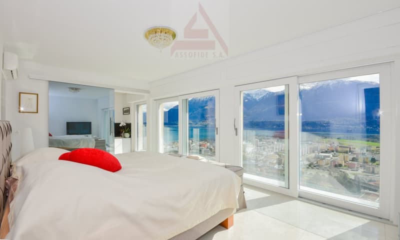 modern decor, large bed, red pillow, glass doors, lake and mountain view