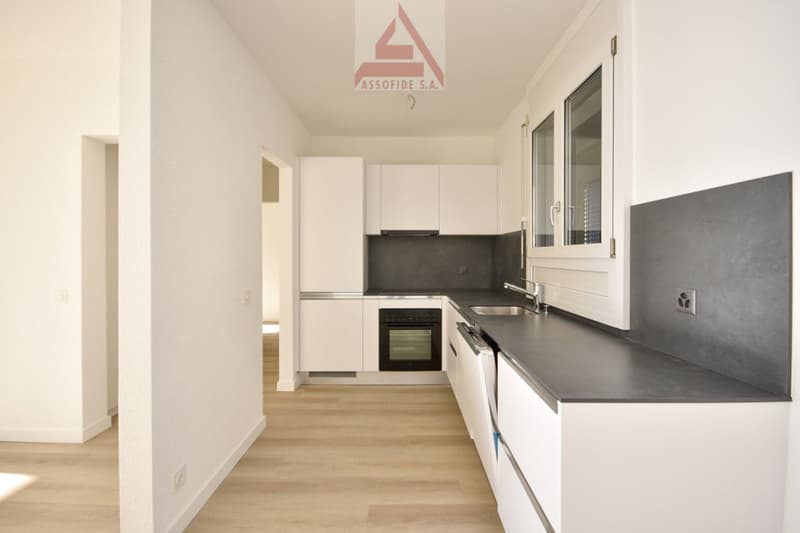 modern kitchen with white cabinets, black countertop, dishwasher, oven, sink, and faucet