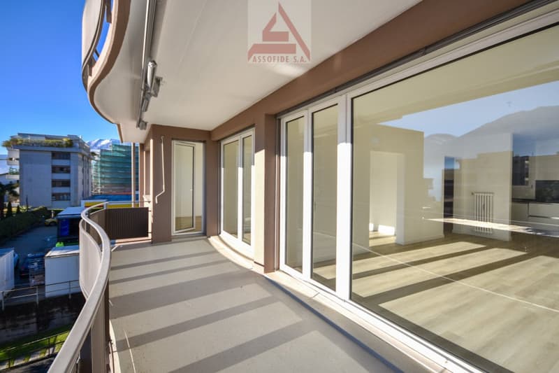 Large balcony, modern railing, sliding glass doors, hardwood flooring