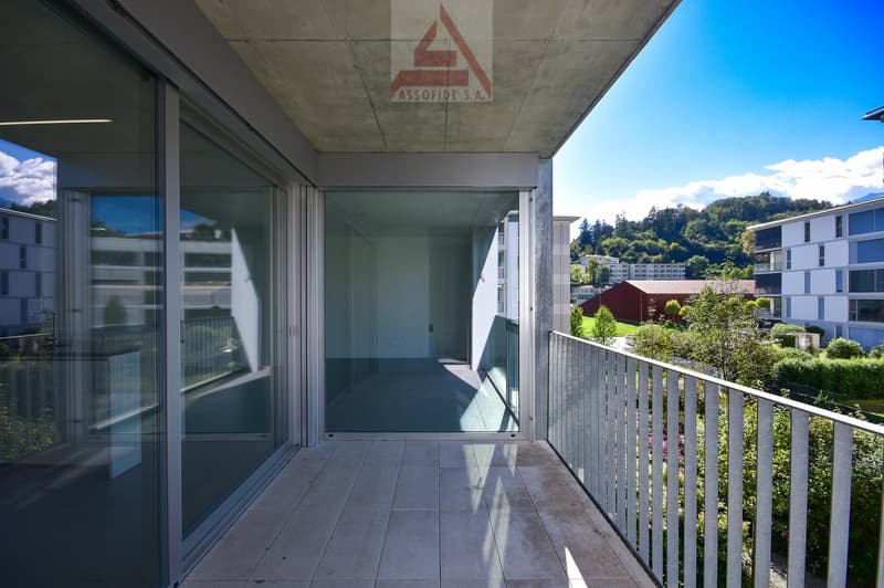 large balcony with full glass walls, metal railing, open to a hallway