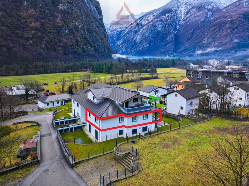 4 story building with mountains in the background, surrounded by grass