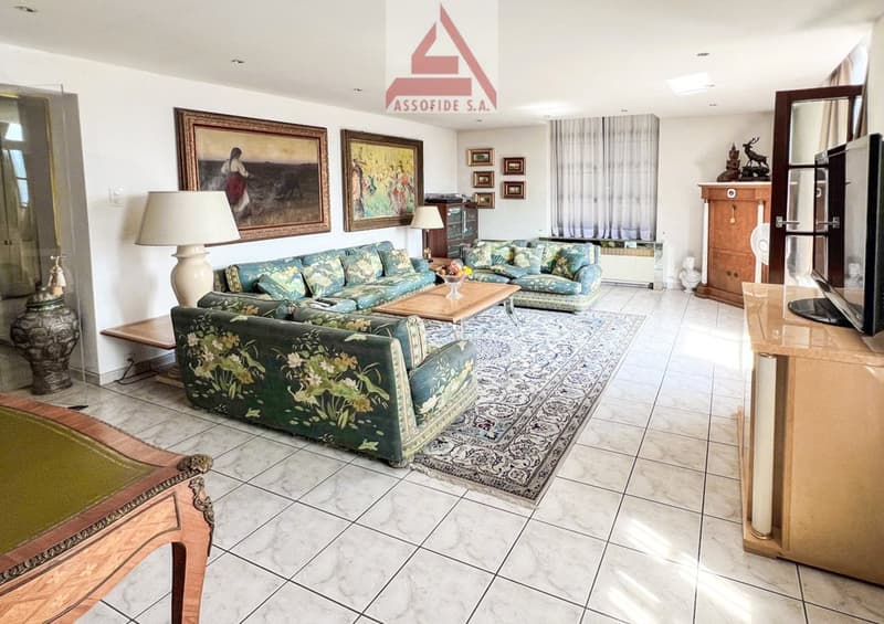 large living room with 3 couches, a coffee table, paintings, a TV, and a lamp