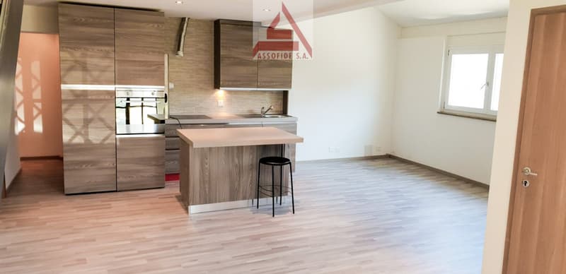 modern kitchen with white walls, wooden floor, kitchen island with a black stool, wooden cabinets, oven, sink, window, tiled backsplash