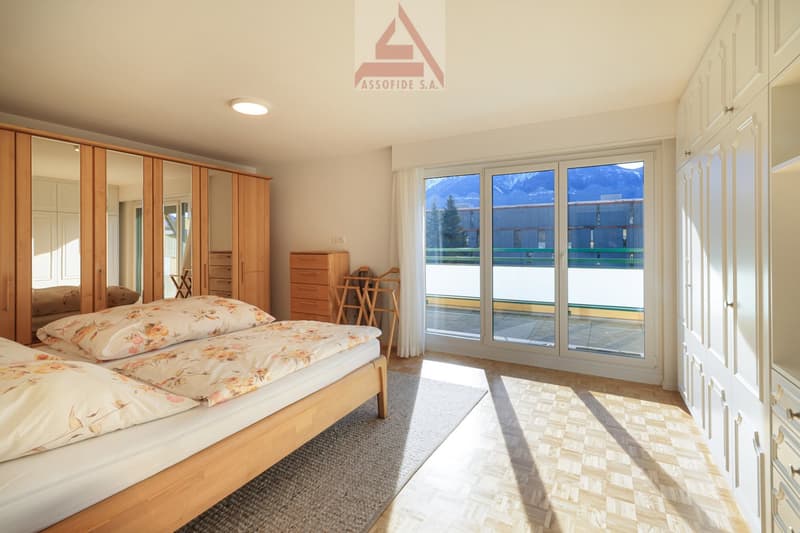 wooden bed, flowery pillowcases, wooden cabinets, sliding glass door, balcony