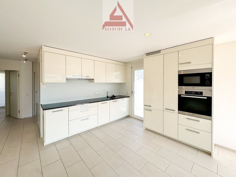 modern kitchen with white cabinets, black countertops, stainless steel appliances, tiled floor