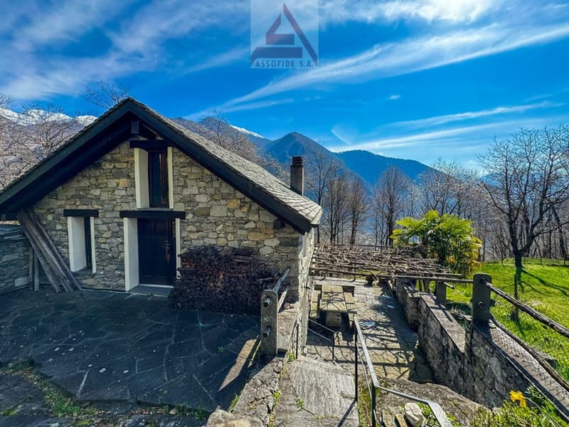 Stone house, wooden door, chimney, stone pathway, wooden fence, green grass, mountain view