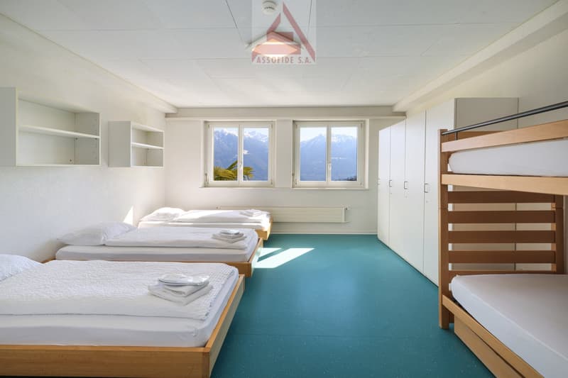 4 single beds, bunk bed, white walls, white ceiling, white shelves, white wardrobe, blue floor, windows with mountain view