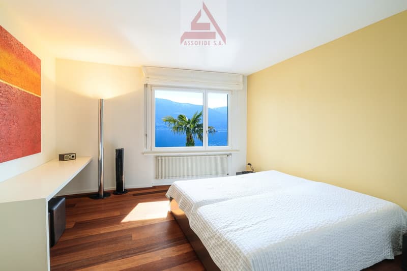 bedroom with two single beds, wooden floor, white walls, large window with view of the sea, desk, radiator, lamp, painting