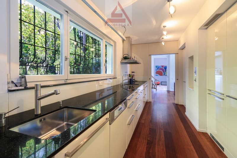 modern kitchen with granite countertops, stainless steel sink, dishwasher, large windows, wooden floor