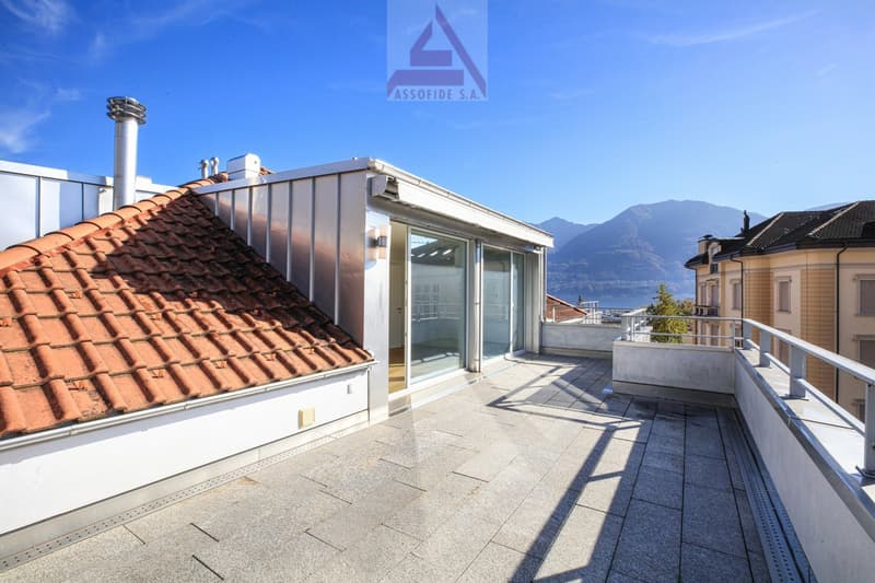 Terrace with tiled floor, metal railing, glass doors, red roof, mountains in the distance