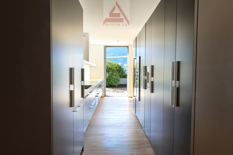 long hallway with wooden floor, modern cabinets, open door to balcony