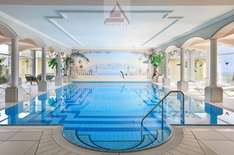 large indoor swimming pool, blue tiles, handrail, decorative columns, mural