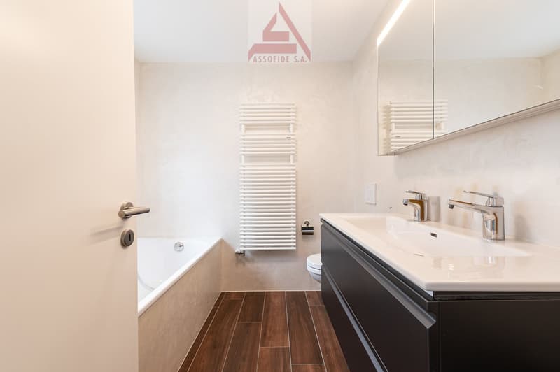 Bathroom with bathtub, sink, toilet, and towel warmer
