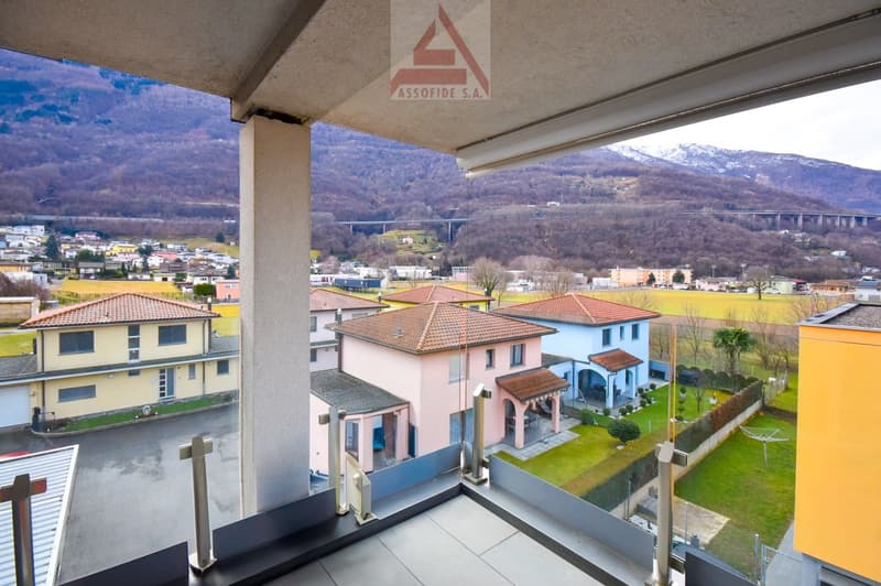 Aerial view of a residential area with houses, mountains, and a bridge in the distance
