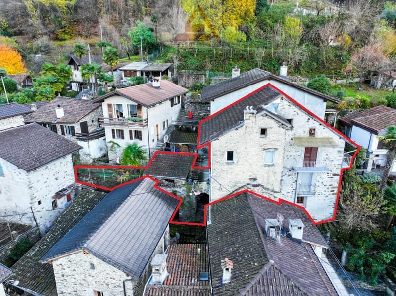Stone houses, multiple buildings, red lines highlighting specific areas, surrounded by trees and plants