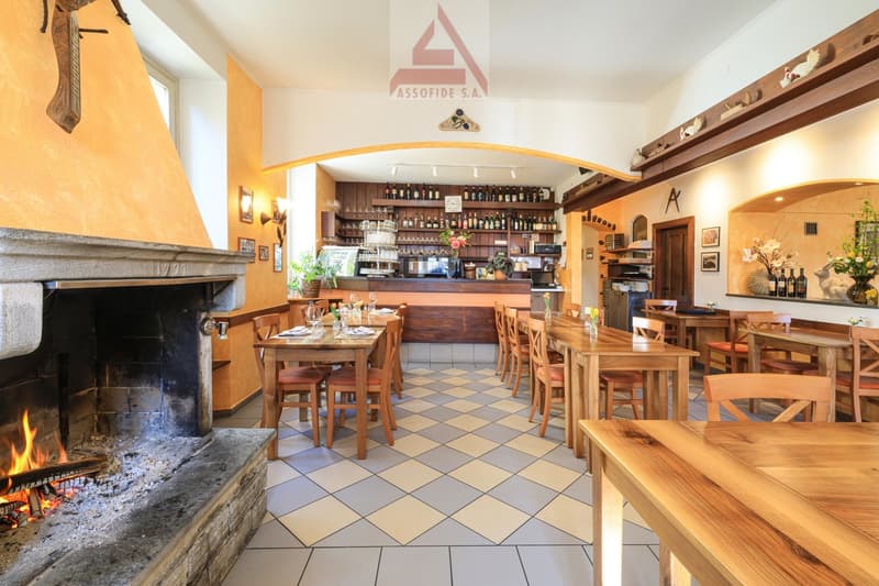wooden tables and chairs, fireplace, wooden bar counter, shelves with bottles, checkered floor
