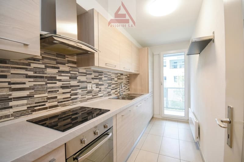 modern kitchen with wooden cabinets, granite countertop, gas stove, oven, sink, faucet, balcony