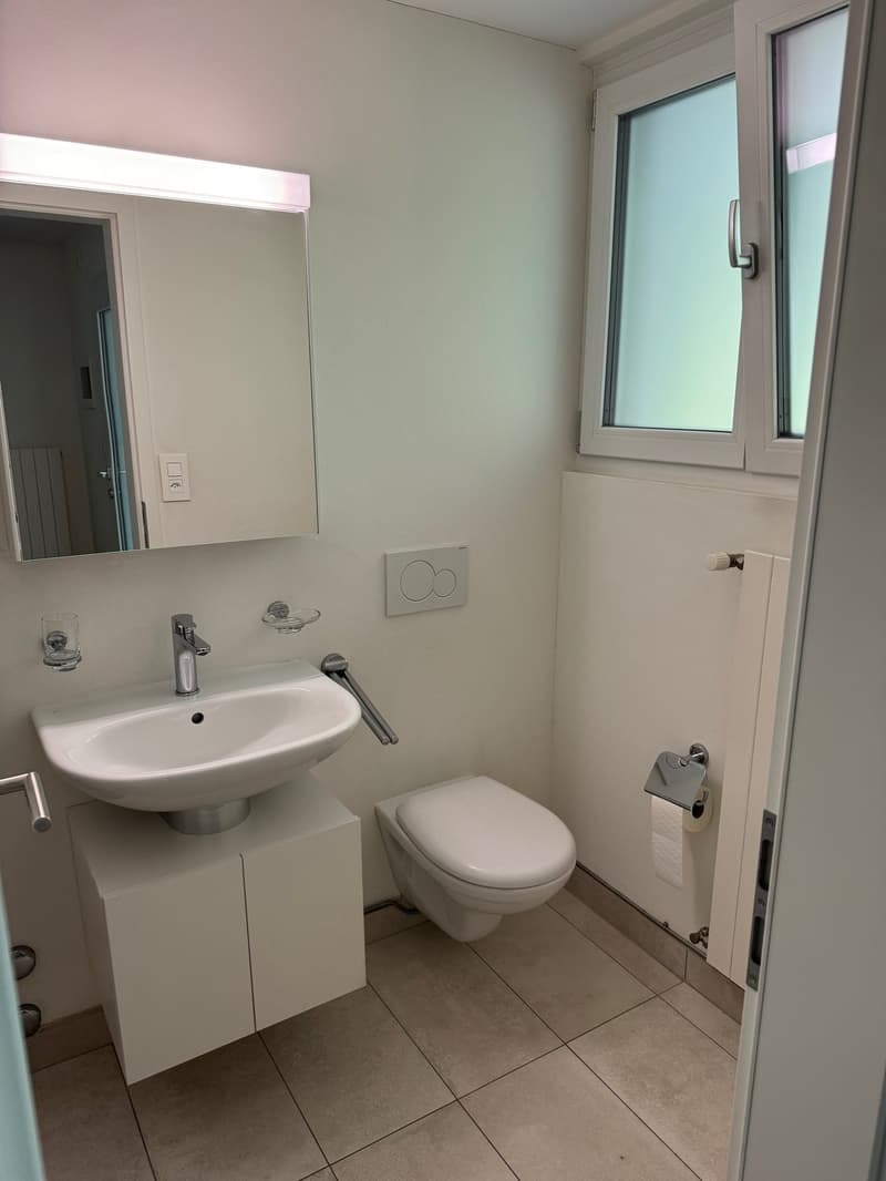 A bathroom with a white sink, a white toilet, and a mirror on the wall.