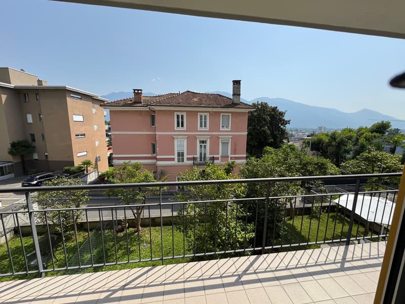 pink facade building with balcony, surrounded by trees and mountains