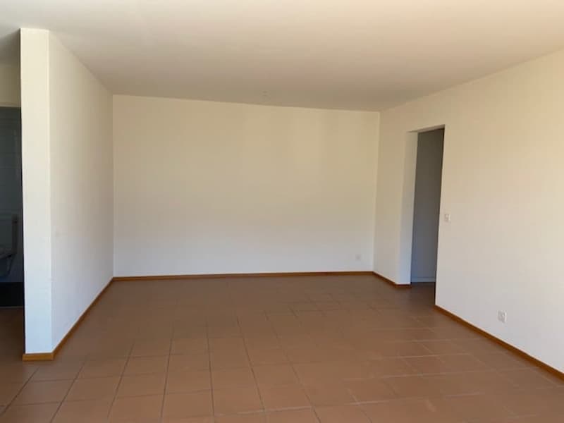 Empty room with brown tiled floor and white walls