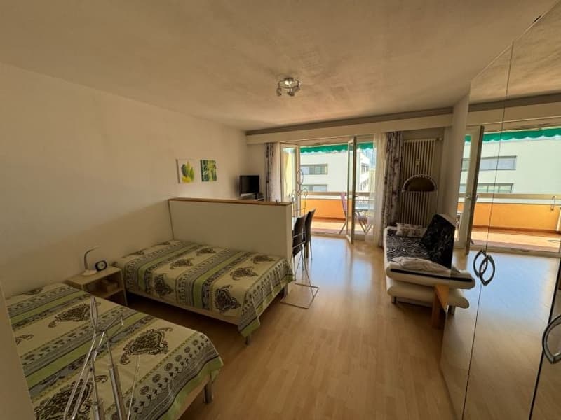 Two single beds, nightstands, couch, table, chairs, sliding glass doors to balcony, TV, radiator, paintings
