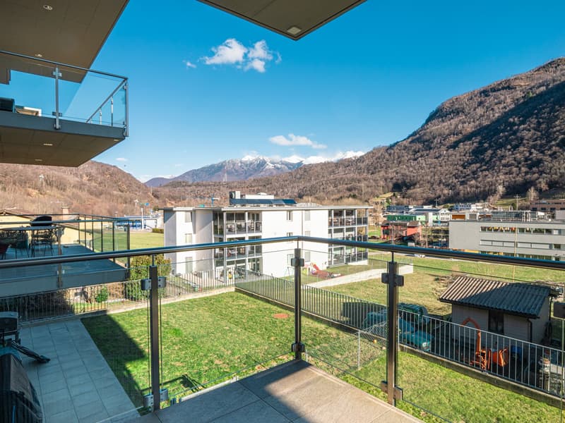 Balcony with a view of the mountains, buildings, and grassy area below
