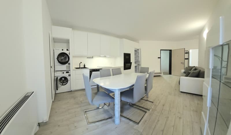 kitchen with a table, a white couch, grey chairs, appliances, white cabinets, wooden floors